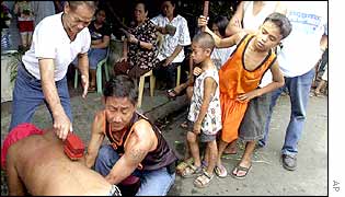 An old man hits the back of a flagellant in suburban Mandaluyong City