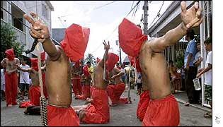 Hooded flagellants kneel in front of a chapel at Mandaluyong, Philippines
