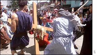 A penitent, dressed as Jesus Christ, is hit by residents of Mandaluyong during a re-enactment of Christ's last days 